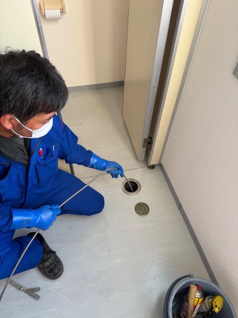 床の掃除口からワイヤーを入れている様子